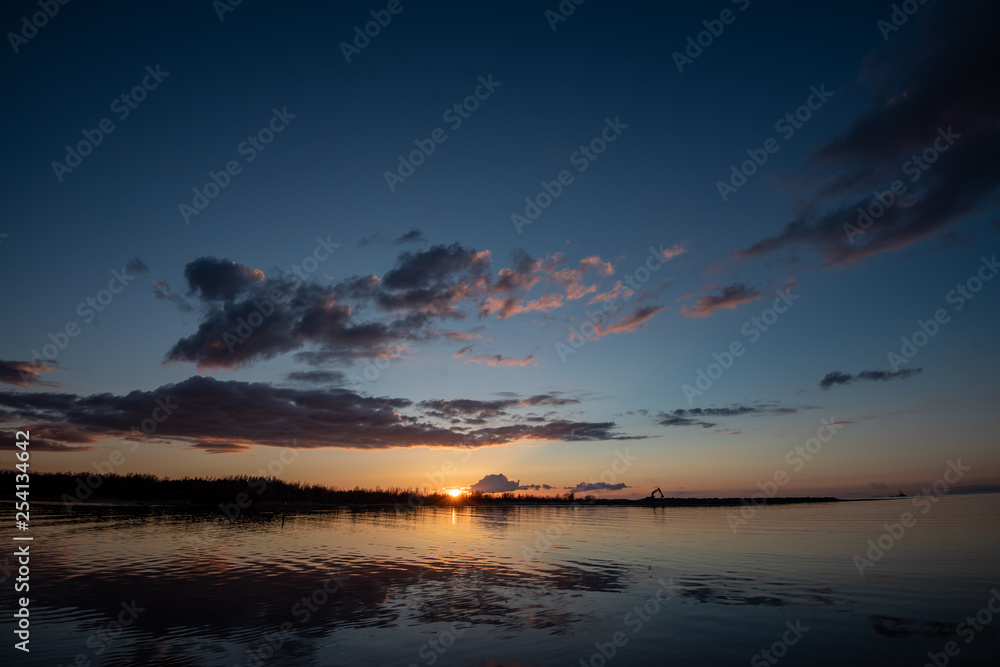 calm lake in bright sun light with reflections of clouds and trees and blue sky calm lake in bright sun light with reflections of clouds and trees and blue sky