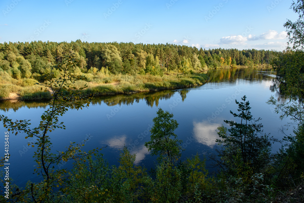 calm lake in bright sun light with reflections of clouds and trees and blue sky calm lake in bright sun light with reflections of clouds and trees and blue sky