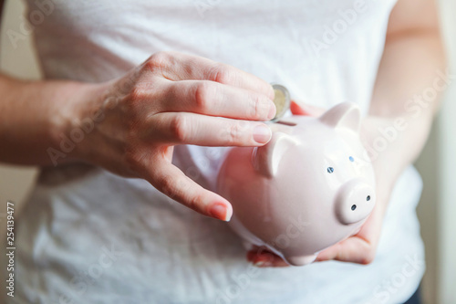Female woman hands holding pink piggy bank and putting money Euro coin. Saving investment budget business wealth retirement financial money banking concept