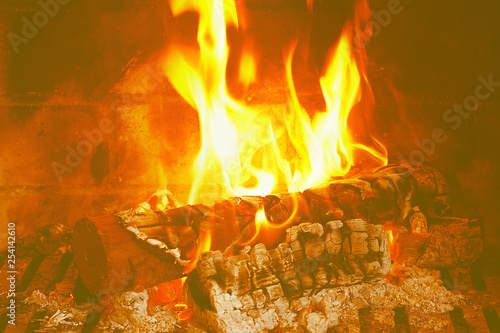 Burning firewood in the fireplace close-up. Close-up with burning logs and vivid burning orange and yellow flames. Flames crawl up the side of a piece of firewood in an open campfire. Toning.