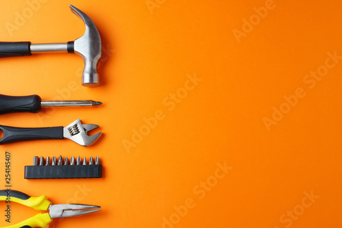 Hammer, pliers, screwdriver on an orange background, top view, a place for an inscription photo