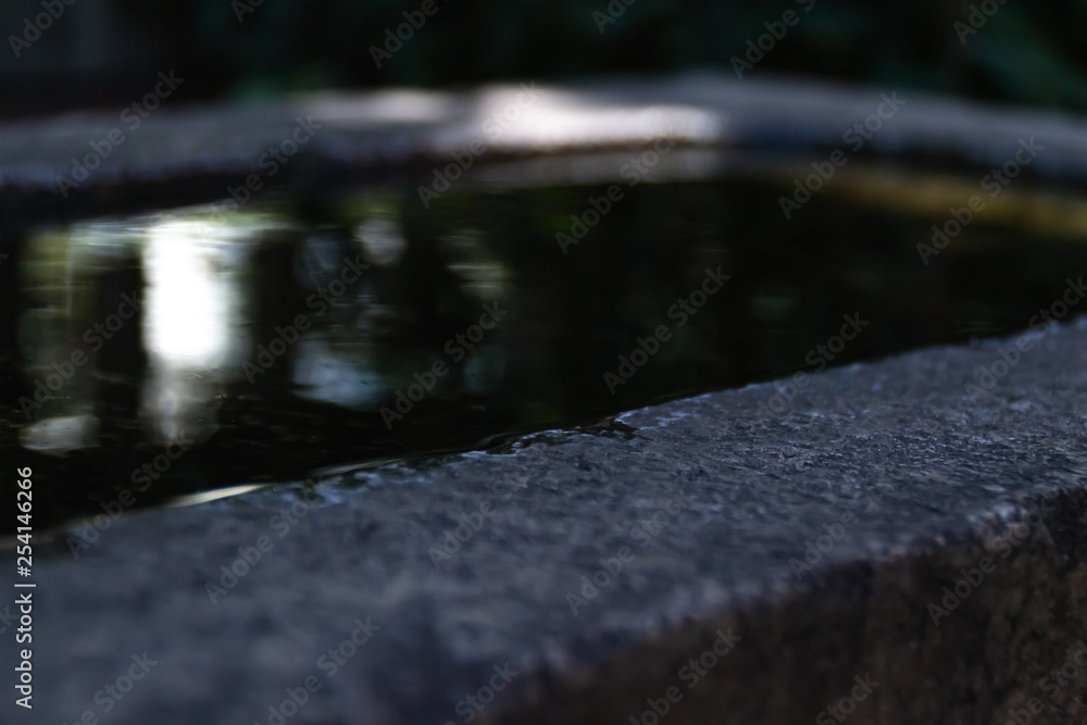 There is clear water in the stone bowl outdoors. There is clear water in the stone bowl outdoors.
