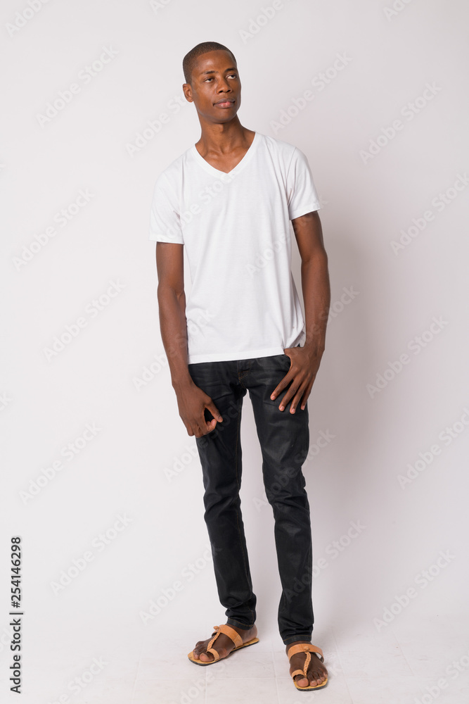 Fototapeta premium Full body shot of young handsome bald African man thinking