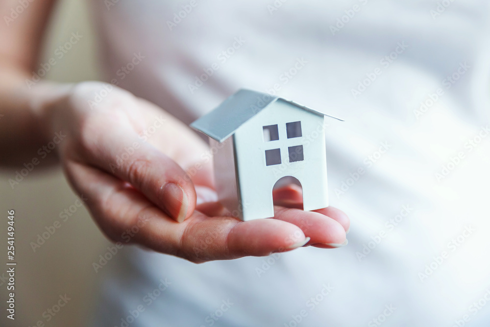 Female woman hands holding small miniature white toy house. Mortgage property insurance dream moving home and real estate concept Female woman hands holding small miniature white toy house. Mortgage property insurance dream moving home and real estate concept