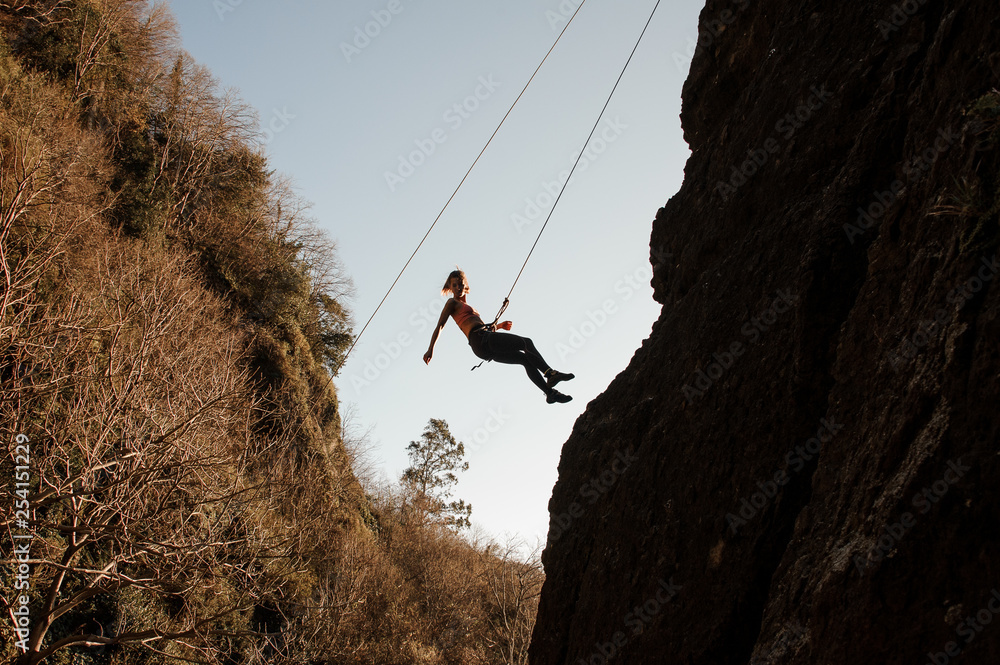 Sloping Rope Girl equipped with a rope abseiling on the sloping rock and looking ...