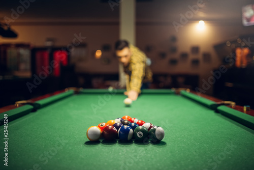 Male billiard player with cue aiming at the table photo