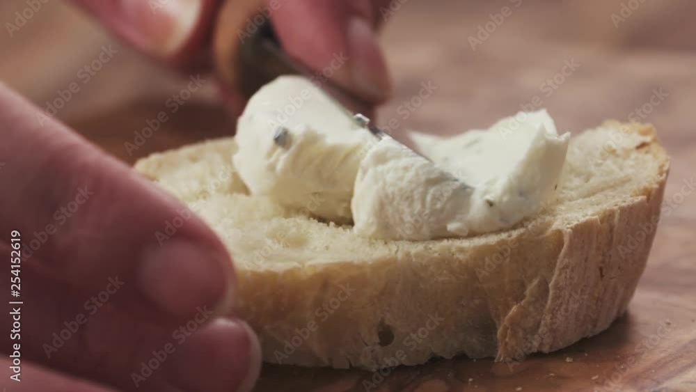 Slow motion closeup of spreading cream cheese on fresh baguette slice Slow motion closeup of spreading cream cheese on fresh baguette slice