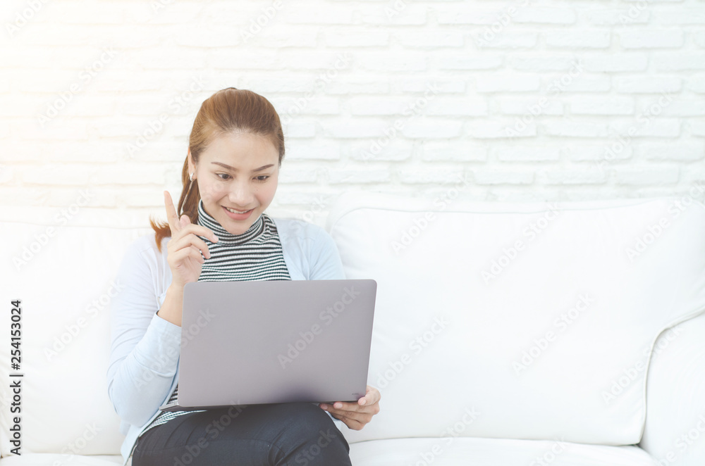 Asian women work with gray laptops on the sofa in the room in the morning.She is thinking hard about her work. Asian women work with gray laptops on the sofa in the room in the morning.She is thinking hard about her work.