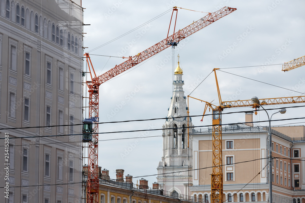 Construction crane in the historic center of Moscow, the Orthodox Church, the bell tower in the background