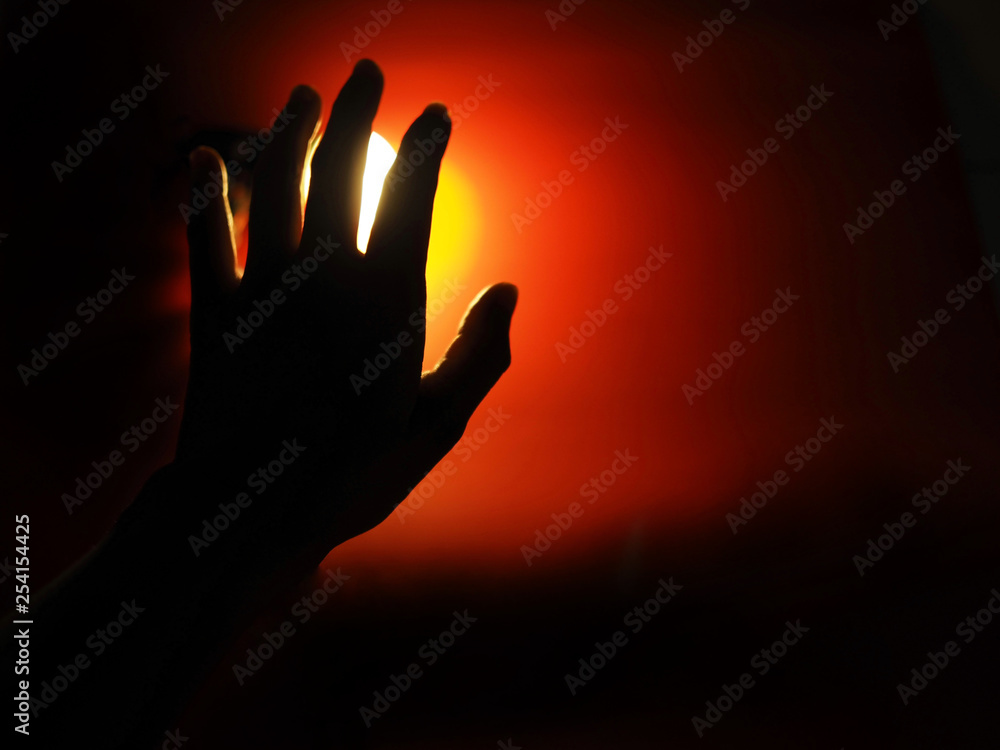 The woman's left hand with yellow light has a red background. The middle of the dark atmosphere.