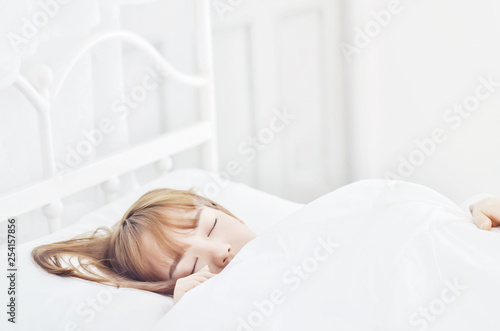 On the bed in the white room.Beautiful woman sleeping in the bedroom.Asian girl sleep well.Sleeping in a white room makes you feel comfortable.Warm tone.