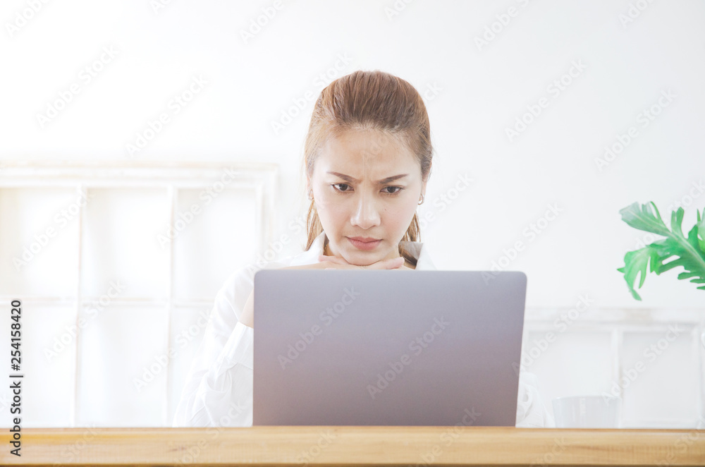 Asian women work with gray laptops on the sofa in the room in the morning.She is thinking hard about her work.Lady sitting in the room. Asian women work with gray laptops on the sofa in the room in the morning.She is thinking hard about her work.Lady sitting in the room.