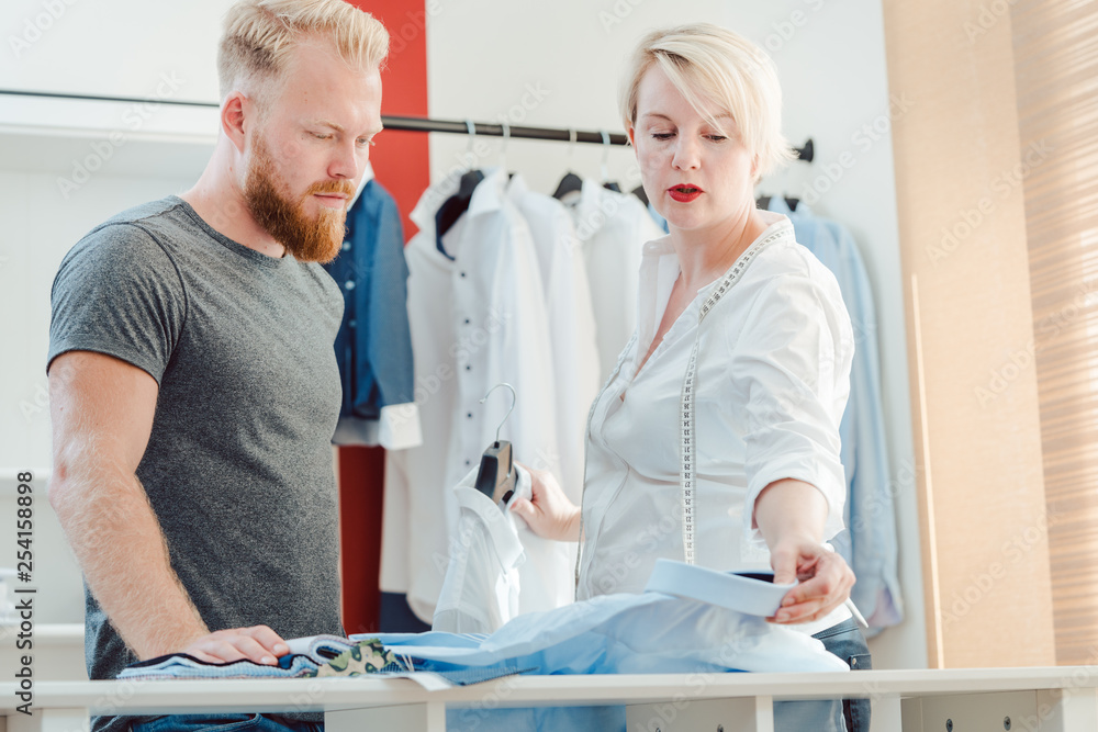 Obraz premium Tailor and customer looking at pattern book choosing materials 