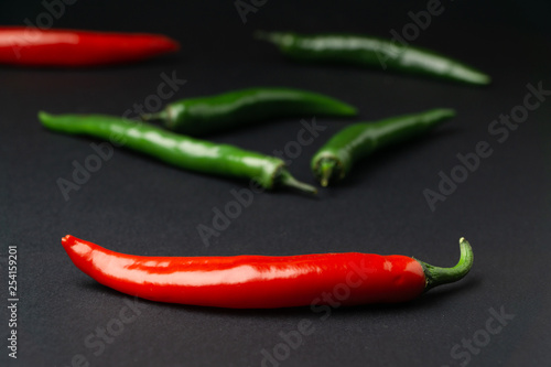 Green and red chili peppers on black background. Hot spicy food symbol.
