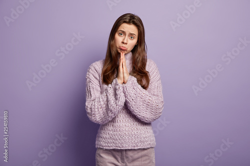Fotografie Sad begging woman has pleading expression, asks for fortune or apologize, purses