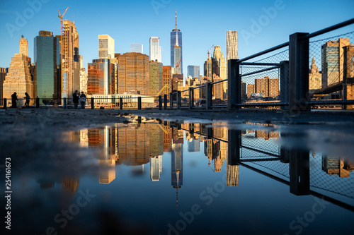 Panorama of lower Manhattan reflected in the water puddle on the walkway of Brooklyn Bridge park, Pier 1.