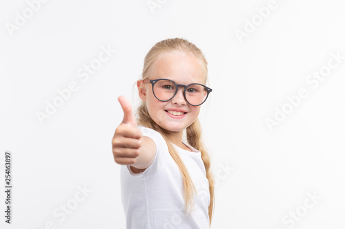 Beautiful child girl with glasses showing thumbs up isolated on white