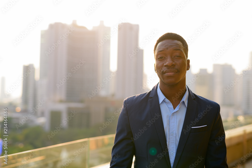 Young handsome African businessman against view of the city Young handsome African businessman against view of the city