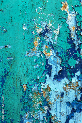 Rusty metal wall, old iron sheet, covered with rust with multi-colored paint. Trace of remnant of old paint in large deep crack on texture of surface rusty metal. Background texture old paint on metal