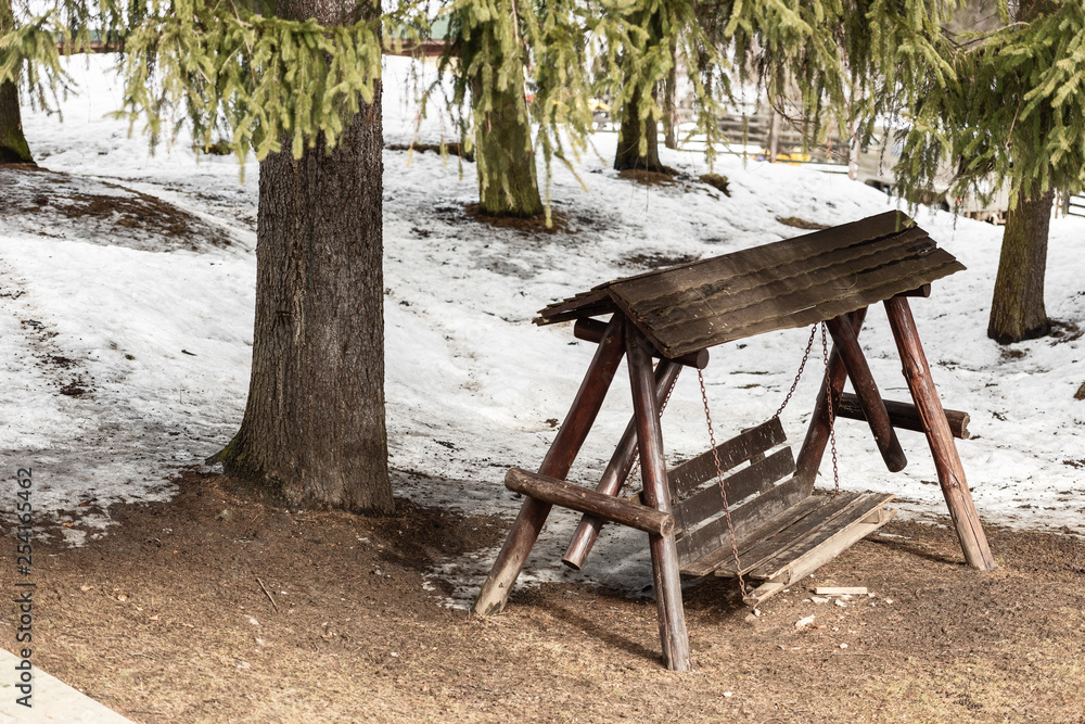 Wooden swing near forest, snowy landscape Wooden swing near forest, snowy landscape
