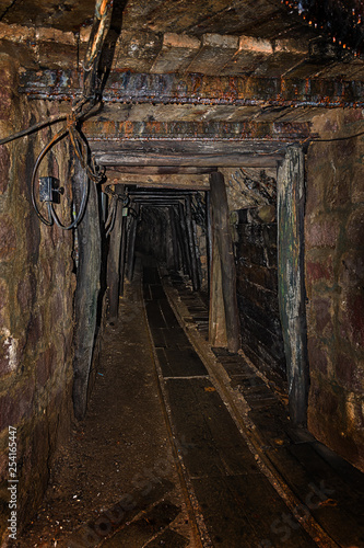 Empty old abandoned mine shaft with wooden timbering and rusty railway © lubos K