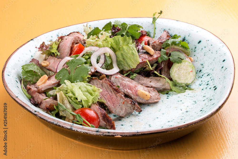 Salad with roast beef and cherry tomatoes on a wooden background