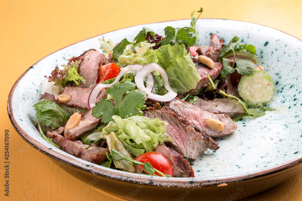 Salad with roast beef and cherry tomatoes on a wooden background Salad with roast beef and cherry tomatoes on a wooden background