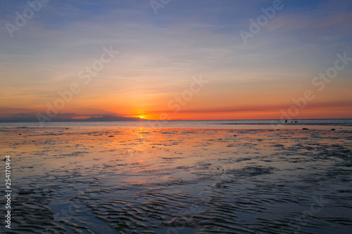 sunset at a beach  the sea in low tide discovered ocean bed  a tranquil scene in a summer evening vacation mood 