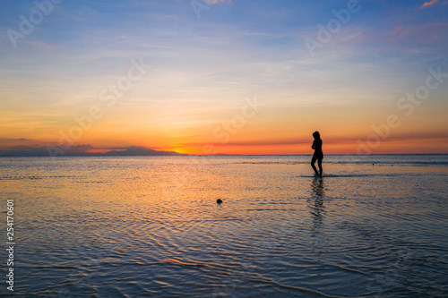Silhouette of a beauty woman walking in the sea by low tide and dusk in a beautiful sunset scenery 