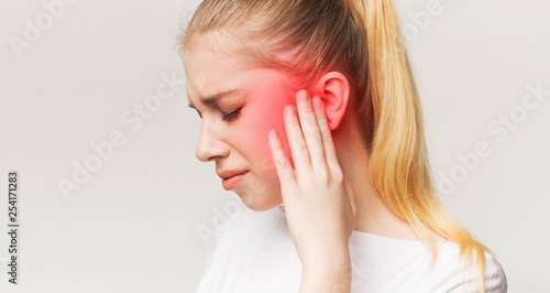 Woman having ear pain, touching her painful head photo