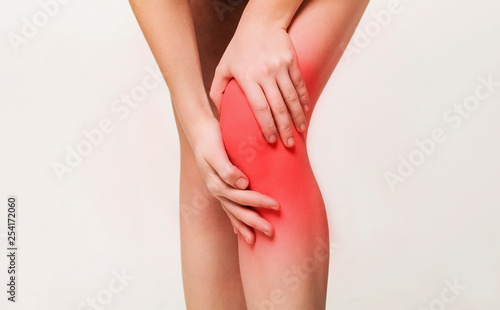 Young woman massaging her painful knee closeup