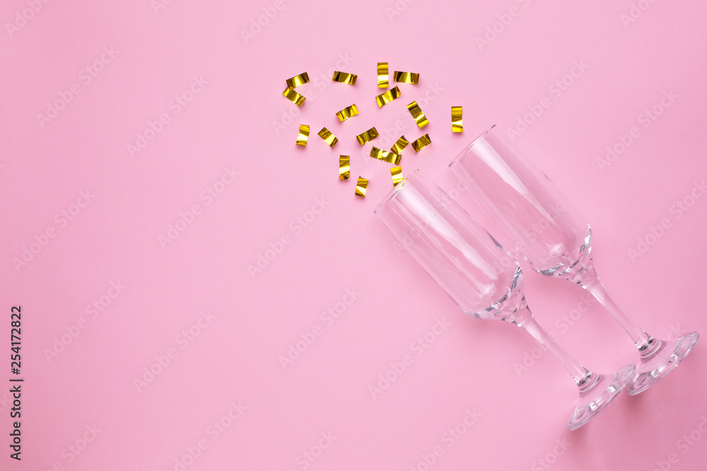 Champagne glasses with golden confetti on pink color paper background minimal style