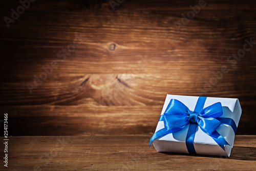 white gift box with blue ribbon on vintage wood