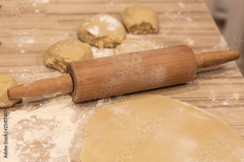 background. a wooden rolling pin with the test lie on a table