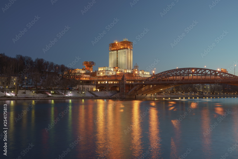 Obraz premium Colorful Moscow park Vorobievy Gory at night winter time. The building of the Academy of Sciences and Andreevsky (Pushkinsky) pedestrian bridge as background. Long exp