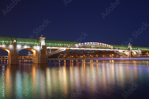 Moskva River in the lights reflections and Andreevsky (Pushkinsky) pedestrian bridge at spring night time. Long exposure image.