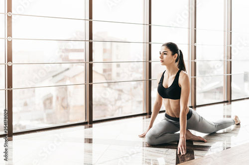 Young slim attractive woman with long hair practicing yoga indoors.