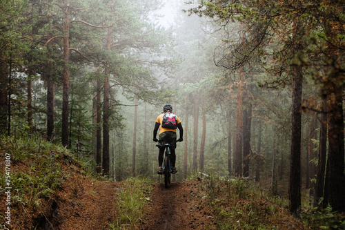 Fotobehang cyclist with backpack riding mountainbike on forest trail in fog