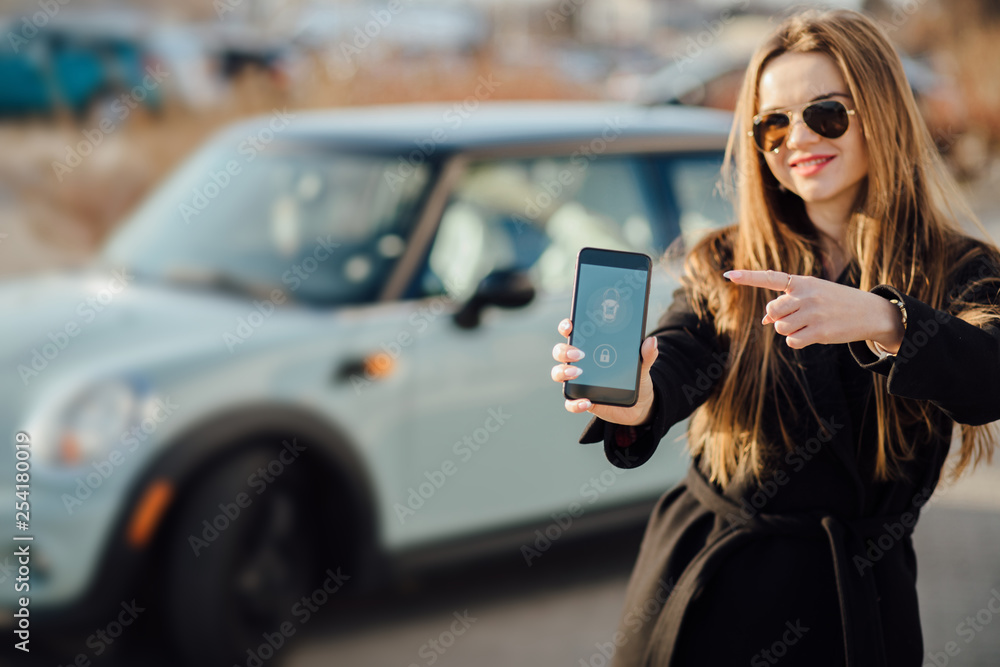 Woman using Smartphone near the car. Mobile phone apps for car owners concept.