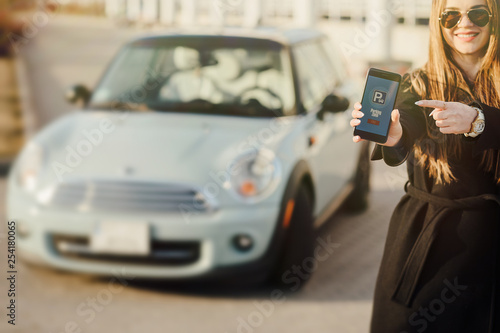 Woman using Smartphone near the car. Mobile phone apps for car owners concept.