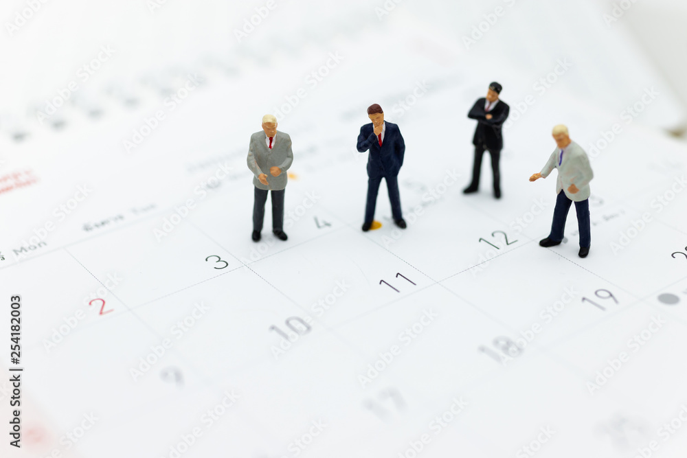 Miniature people : Businessman standing on the calendar to set the date for the meeting . Image use for business meetings concept. Miniature people : Businessman standing on the calendar to set the date for the meeting . Image use for business meetings concept.