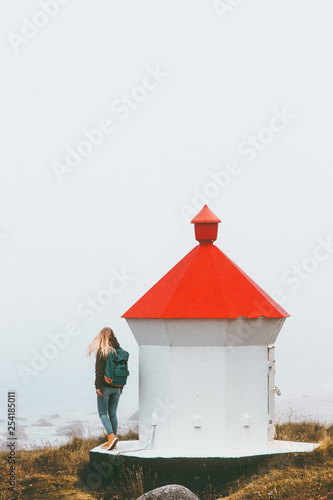 Woman tourist walking near lighthouse Travel lifestyle adventure trip outdoor in Norway foggy seaside on background