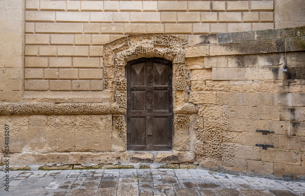 Lecce, Puglia, Italy - Medieval historical center in the old town. View and detail of an ancient gate or door. A region of Apulia Lecce, Puglia, Italy - Medieval historical center in the old town. View and detail of an ancient gate or door. A region of Apulia