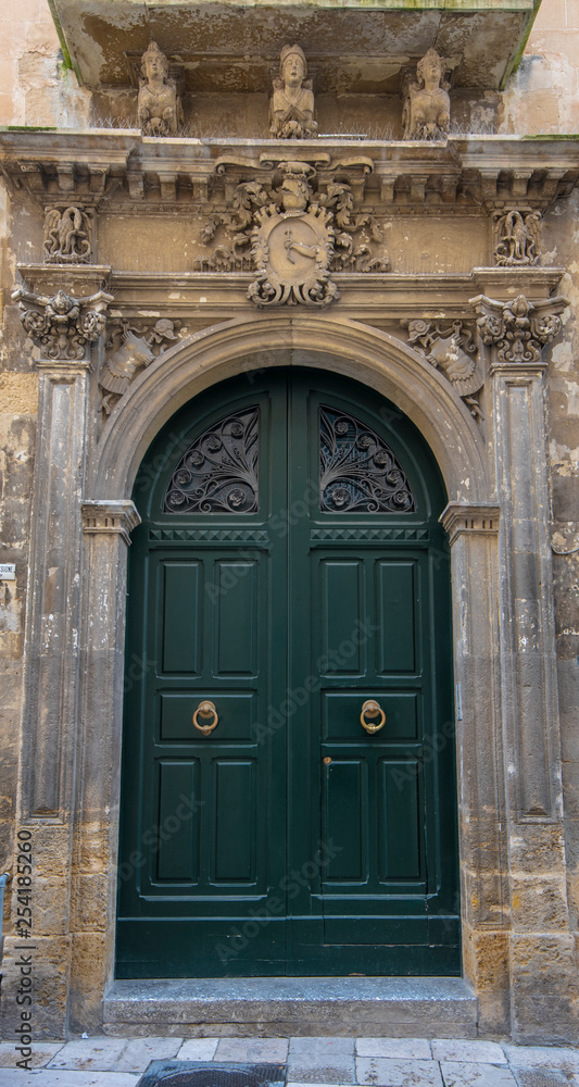 Lecce, Puglia, Italy - Medieval historical center in the old town. View and detail of an ancient gate or door. A region of Apulia Lecce, Puglia, Italy - Medieval historical center in the old town. View and detail of an ancient gate or door. A region of Apulia