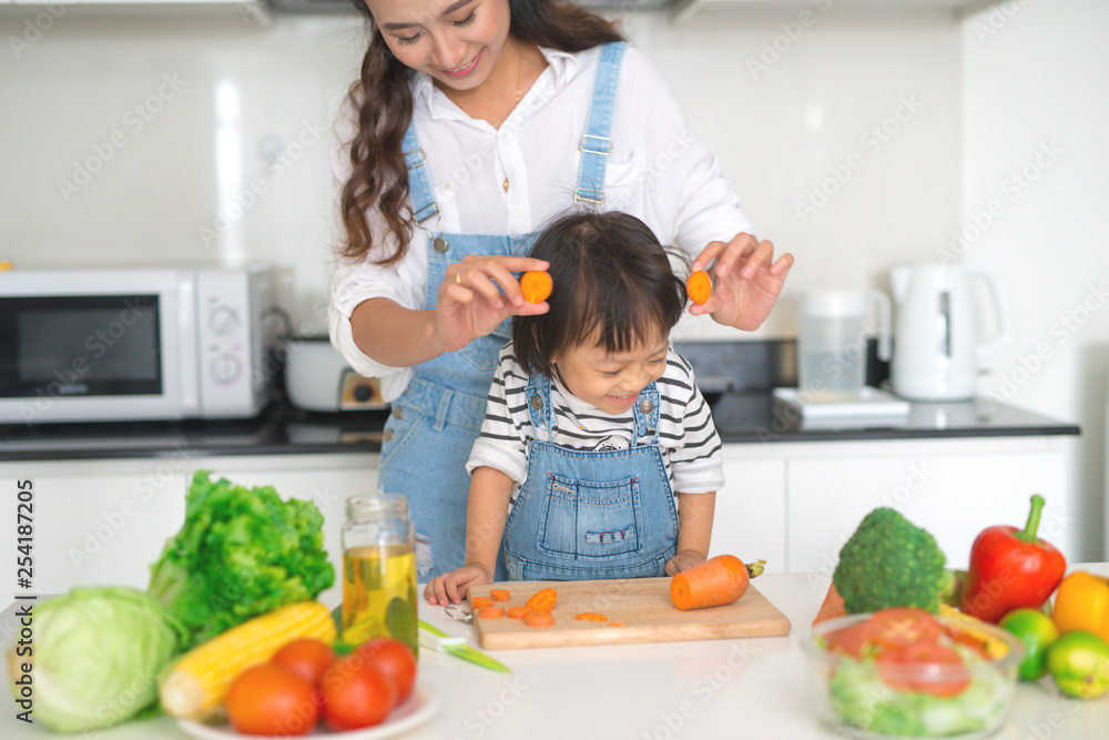 Happy family in the kitchen. Mother and child daughter are preparing the vegetables and fruit. Happy family in the kitchen. Mother and child daughter are preparing the vegetables and fruit.