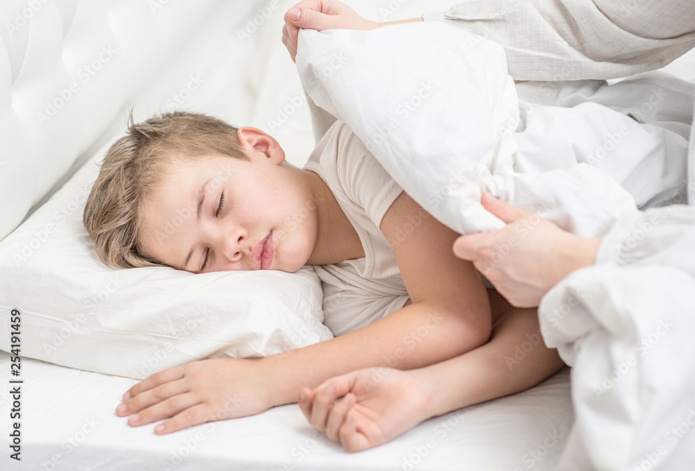 Mother covering little sleeping boy with blanket Mother covering little sleeping boy with blanket