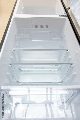 Open new fridge. Empty refrigerator with open door, view from below.