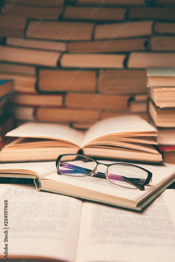 Open book and glasses on wood desk in the library room with blurred focus for education background and back to school concept Open book and glasses on wood desk in the library room with blurred focus for education background and back to school concept