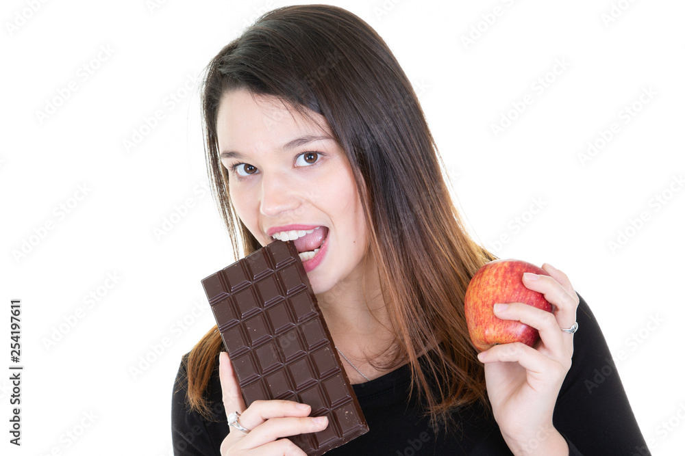 young woman hesitating between a chocolate and an apple young woman hesitating between a chocolate and an apple