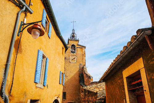 France. Provence. Roussillon tourist village. The old bell tower and houses with ocher on the blue sky background. photo